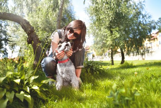 happy caucasian woman in sunglasses resting in nature with her beloved dog schnauzer.