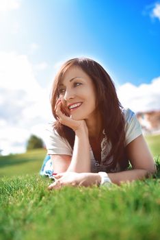 summer-vacation, adult woman relaxed lying on green grass in an outdoor park. girl in sunglasses enjoying nature lying on grass