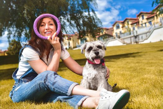 Caucasian joyful woman playing with her beloved dog in the park. The concept of love for animals. best friends. Dog breed Schnauzer