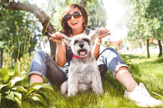 happy caucasian woman in sunglasses resting in nature with her beloved dog schnauzer.