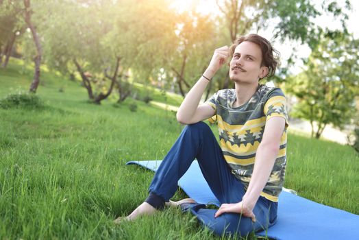 handsome stylish guy enjoys nature and dreams about something sitting in the park. peaceful sight. summer mood