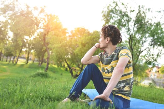 handsome stylish guy enjoys nature and dreams about something sitting in the park. peaceful sight. summer mood