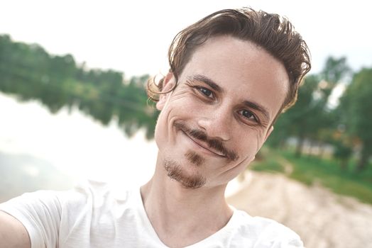 Handsome caucasian guy takes a selfie at the beach - people, lifestyle