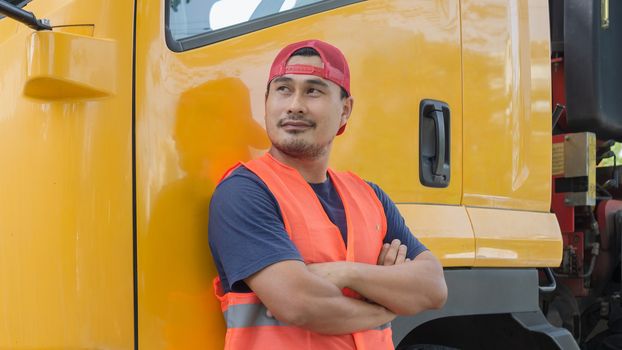 An Asian man was smiling happily beside the yellow truck. He has a career as a transport driver. The transportation business never stops. It must be driven and traveled all the time.