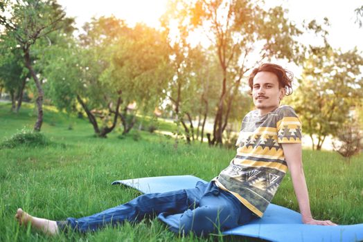 handsome stylish guy enjoys nature and dreams about something sitting in the park. peaceful sight. summer mood