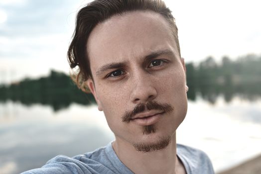 Handsome caucasian guy takes a selfie at the beach - people, lifestyle