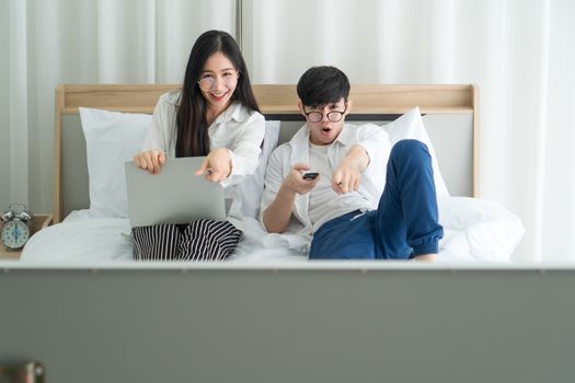 Asian men and women are happily at home. They are using laptops, working and watching news and other TV programs. Staying safe Keep yourself away from society Preventing Covid-19 Infection