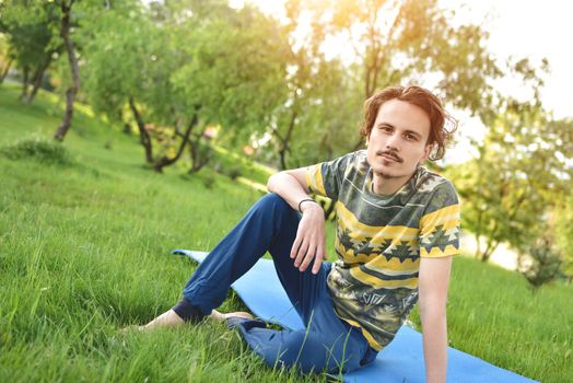 handsome stylish guy enjoys nature and dreams about something sitting in the park. peaceful sight. summer mood