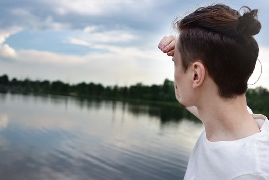 Man looks into the distance near a lake and forest. Enjoys a beautiful view. summer . spring nature