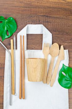 Zero waste concept. Textile eco bags, wooden glass and bamboo utensil on wooden background. Eco friendly and reuse concept. Top view or flat lay