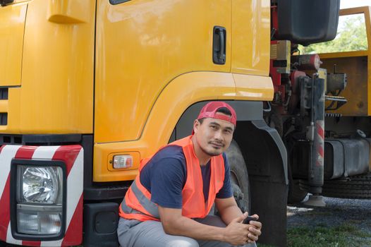 An Asian man was smiling happily at the yellow truck. He has a career as a transport driver. The transportation business never stops. It must be driven and traveled all the time.