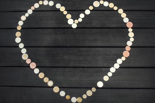 Scattered coins of different countries in the form of a question mark and an exclamation point on wooden table.