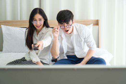 Asian men and women are happily at home. They are using laptops, working and watching news and other TV programs. Staying safe Keep yourself away from society Preventing Covid-19 Infection