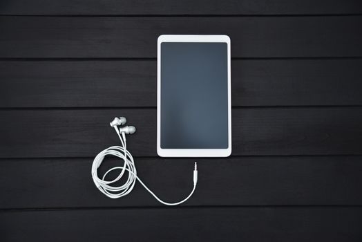 technology, music, gadget and object concept - close up of white smartphone , tablet pc and earphones on wooden background