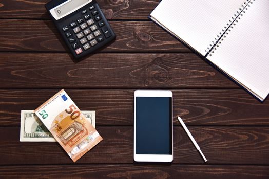 Top view of tablet, smartphone, calculator, notepad on white background, planning personal income, financial concept. Hand is typing on the calculator for money plan.