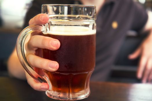 Dark beer in mans hand,mug of beer,