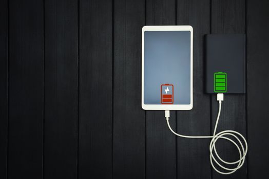 power bank loads tablet PC, smartphone - isolated on wooden background. charging concept. free copyspace