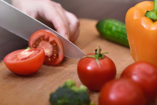 Man slicing a tomato , Bell peppers, and cucumbers with a chef's knife. Organic ingredients for healthy eating