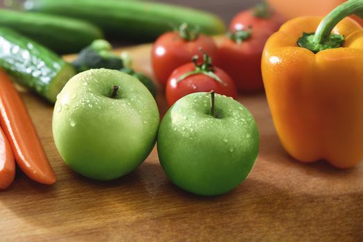 Fresh fruits and vegetables on the old wooden board. apples . carrots. cucumbers. pepper.tomatoes. broccoli