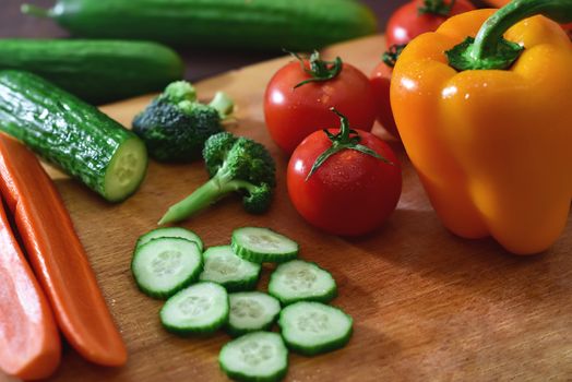 Nature Gifts. Benefits for the body. Fresh sliced vegetables lie on a wooden table. Tomatoes .cucumbers. broccoli. pepper. carrots.