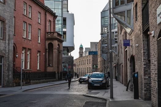 Dublin, Ireland - February 16, 2019: people walking down a small street with typical architecture of small downtown areas on a winter day
