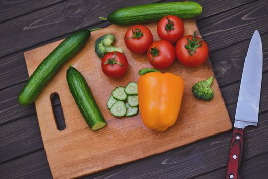 Nature Gifts. Benefits for the body. Fresh sliced vegetables lie on a wooden table. Tomatoes .cucumbers. broccoli. pepper. carrots.