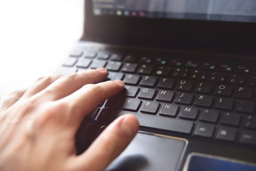 Close-up of male hands typing on laptop keyboard