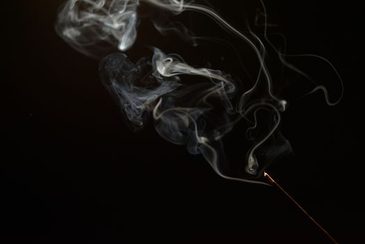 smoldering aromatic stick in the dark, a lot of smoke