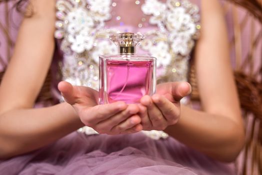 Teen girl with pink parfume bottle in her little hands