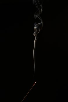 smoldering aromatic stick in the dark, a lot of smoke