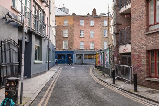 Dublin, Ireland - February 16, 2019: people walking down a small street with typical architecture of small downtown areas on a winter day