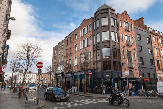 Dublin, Ireland - February 16, 2019: people walking down a small street with typical architecture of small downtown areas on a winter day