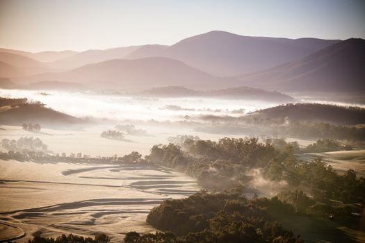 A view across a valley at sunrise in the Yarra Valley in Victoria, Australia