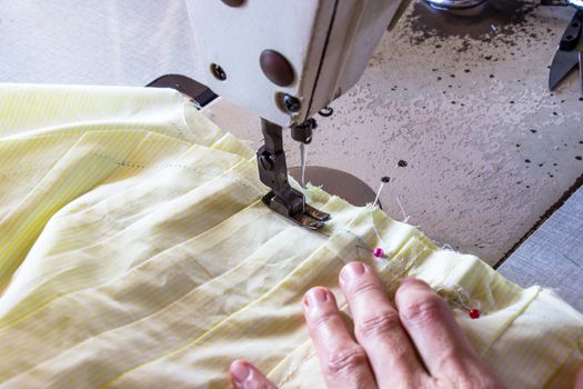 Image women's hands of seamstress working on sewing machine.