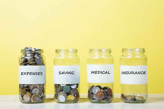 Coins in glass jar contains coins for medical, expenses, insurance and savings. Medical concept.