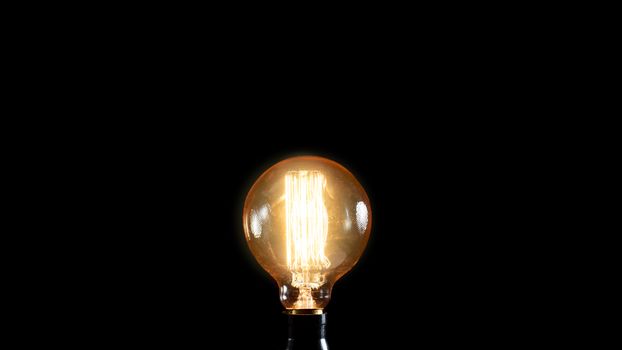 Vintage Edison lamp on black background. Creative idea concept.