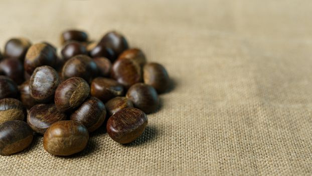 Roasted sweet chestnuts on rustic wooden table.