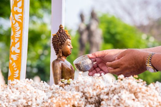 People pour water over Buddha statues during the Songkran Days or traditional Thai New Year.