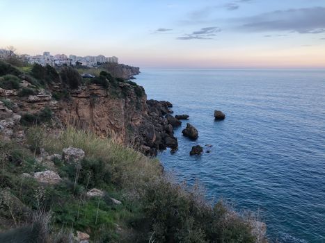Landscape of blue Mediterranean sea rocks sunset and cloudy sky in Antalya