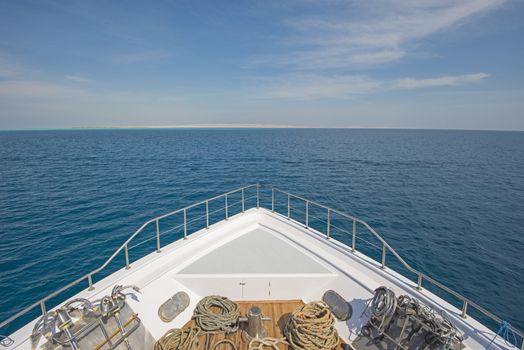View over the bow of a large luxury motor yacht on tropical open ocean with anchors