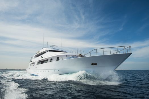 A luxury private motor yacht under way on tropical sea with bow wave