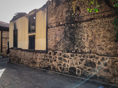 Ruins of burned ancient historical 2 floors house after fire disaster accident in old town of Antalya Kaleici Turkey. Stock image of heaps of ash and arson, collapsed roof and broken windows.