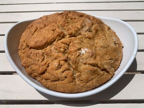 Round home made dark bread in a white plate. Horizontal stock image.