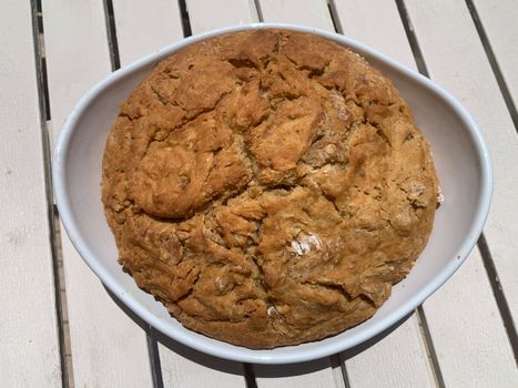 Round home made dark bread in a white plate. Horizontal stock image.