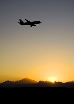 Passenger aircraft coming into land silhouetted in the sunset