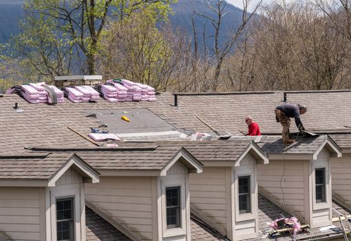 Morgantown, WV - 18 April 2020: Roofing contractors replacing the old shingles on a townhouse roof