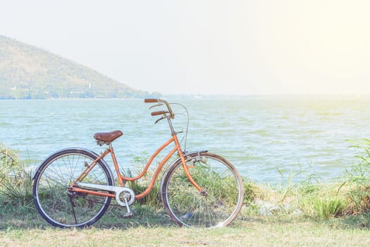 Orange bicycle with the backdrop of the mountains and the sea with warm sunshine.
