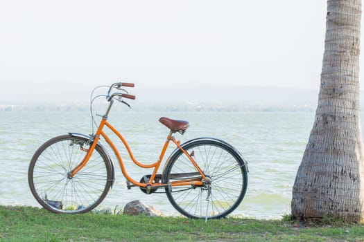 Orange bicycle with the backdrop of the mountains and the sea with warm sunshine.