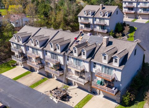 Morgantown, WV - 22 April 2020: Aerial view of roofing contractors replacing the old shingles on a townhouse roof