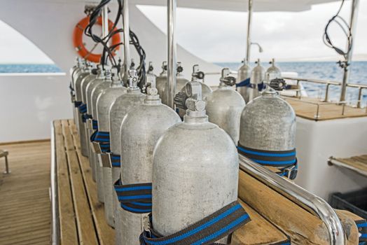 Row of aluminium scuba diving cylinders on dive deck of a luxury liveaboard motor yacht boat